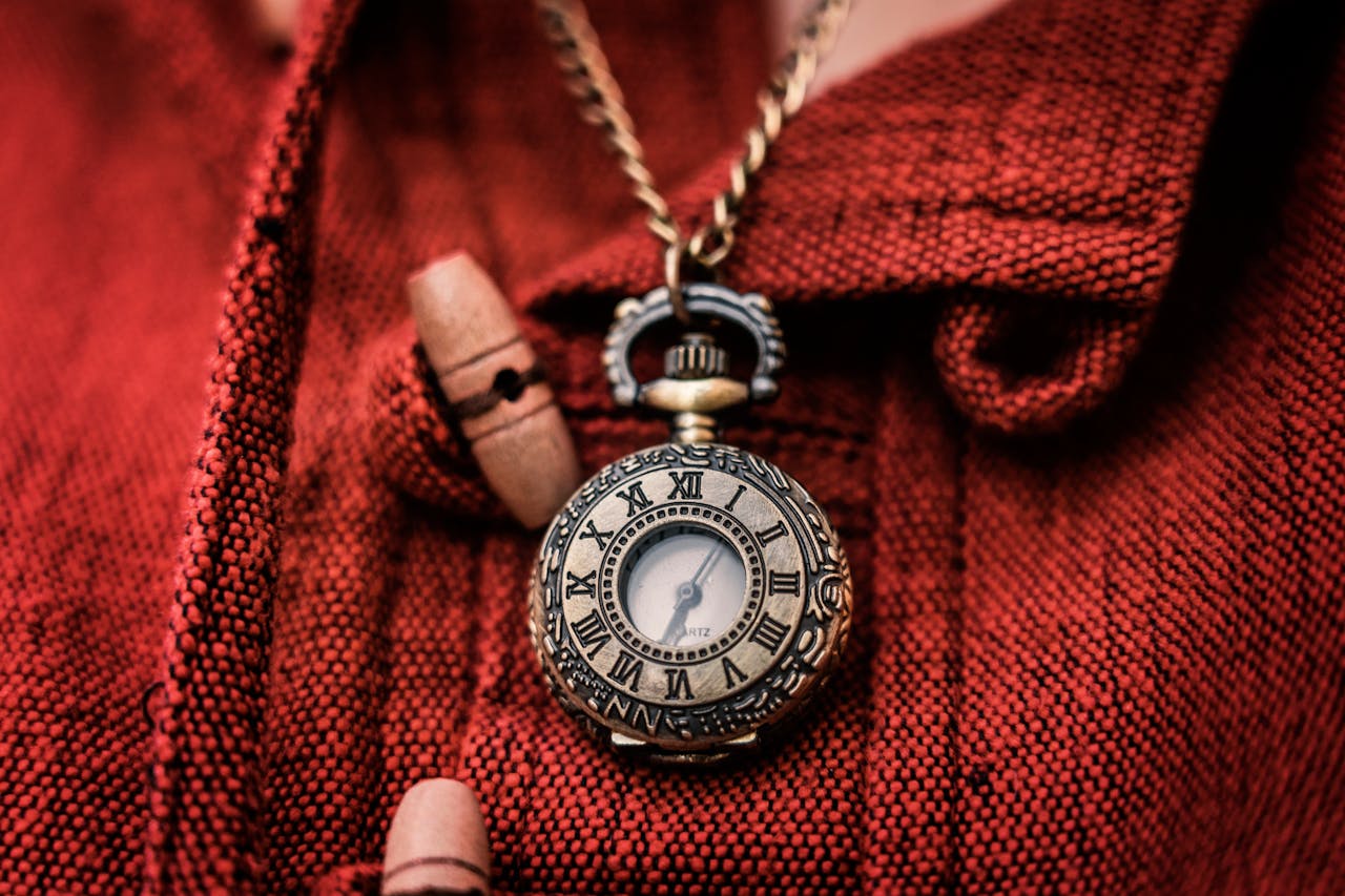 Close-up of a vintage pocket watch with Roman numerals against a textured red background.